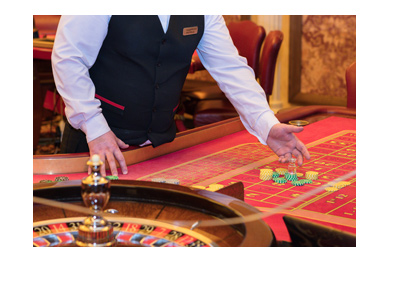 Male live roulette dealer presenting the red felt table.